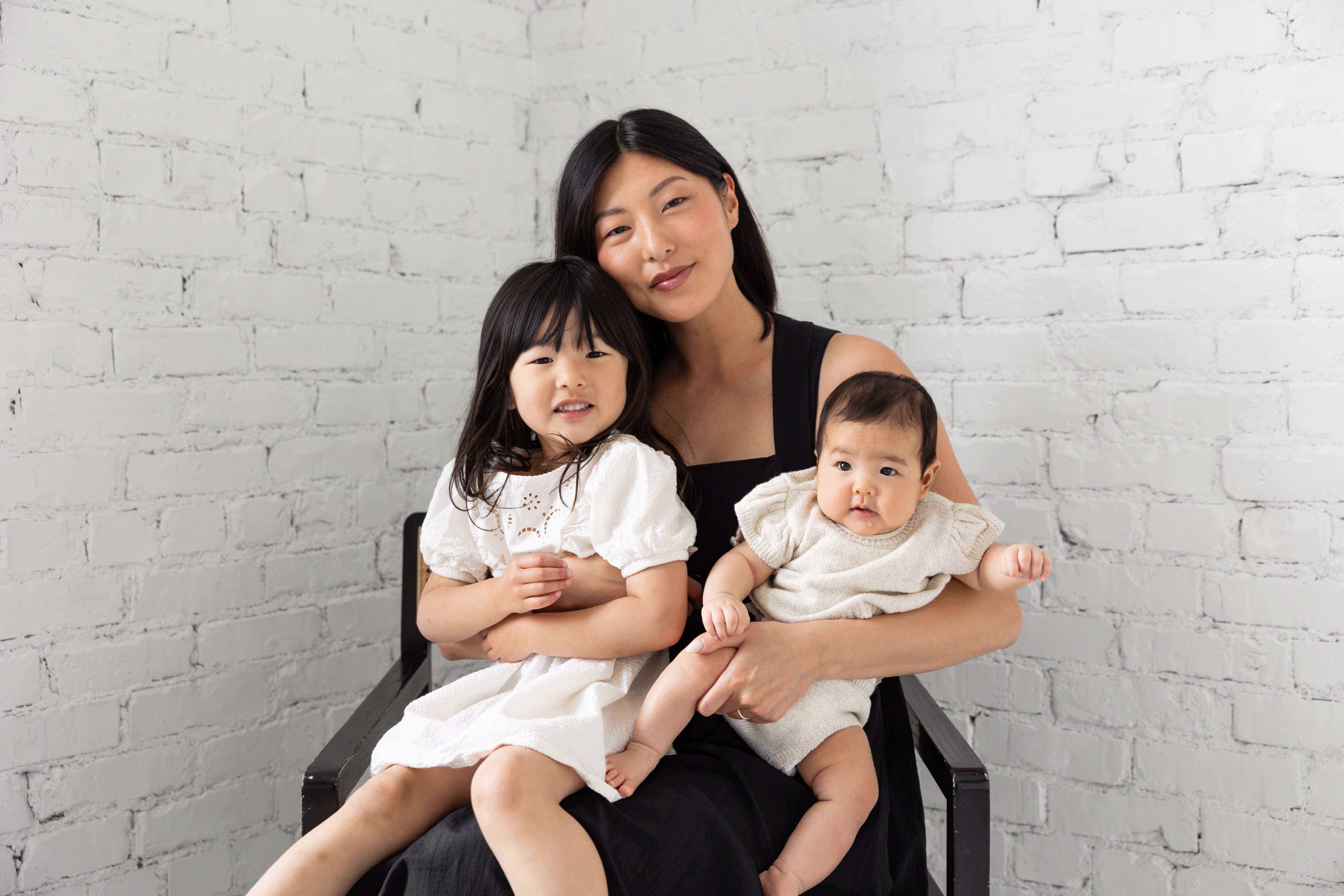A mother with her two children wearing neutral dresses for Mother's day.