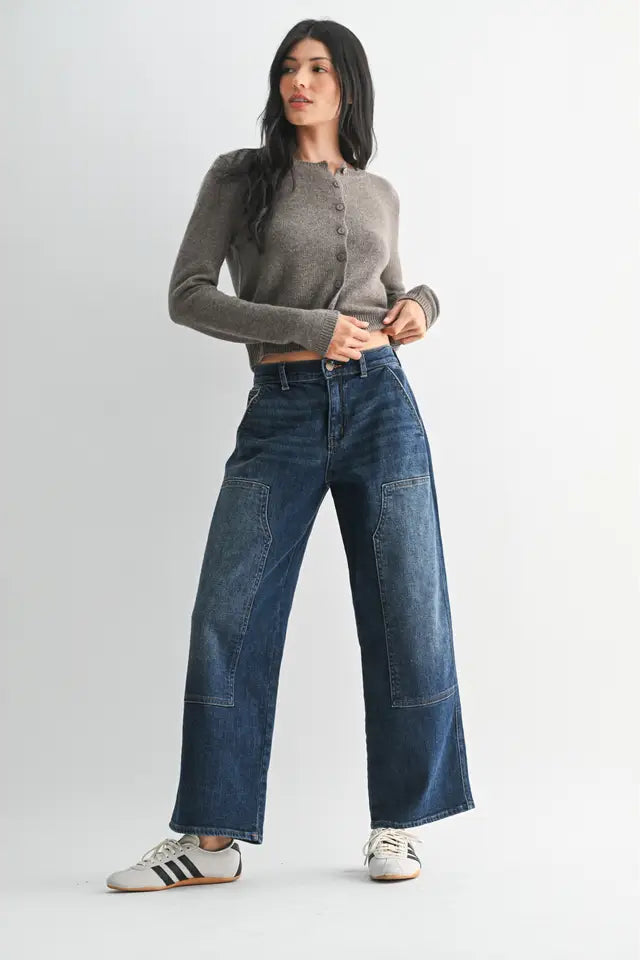 Woman wearing a gray button-up shirt and blue jeans on a white background