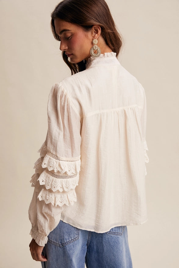 Woman wearing a white blouse with lace details and blue jeans on a beige background