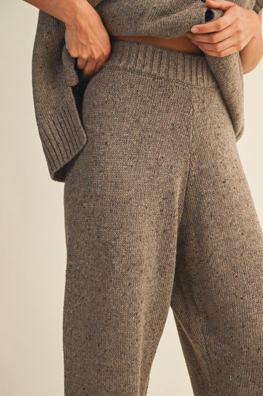 Brown knitted outfit with pants and cardigan on a neutral background