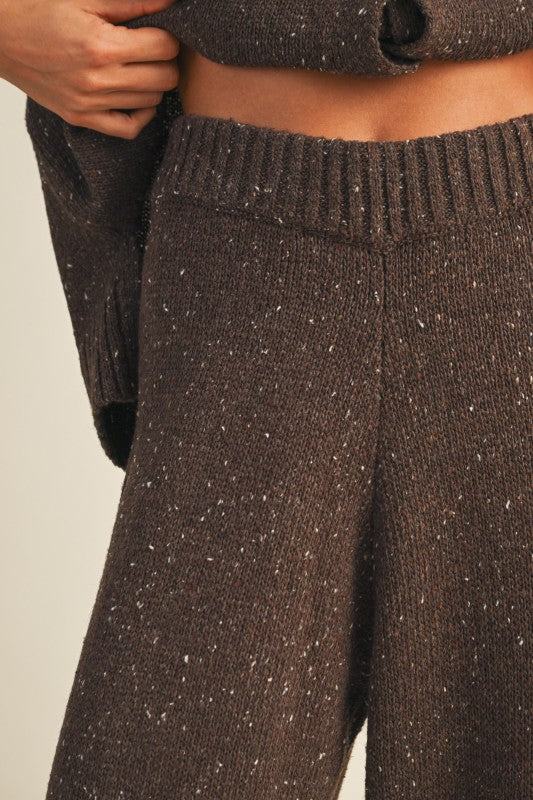 Brown knitted pants with speckled pattern on a neutral background