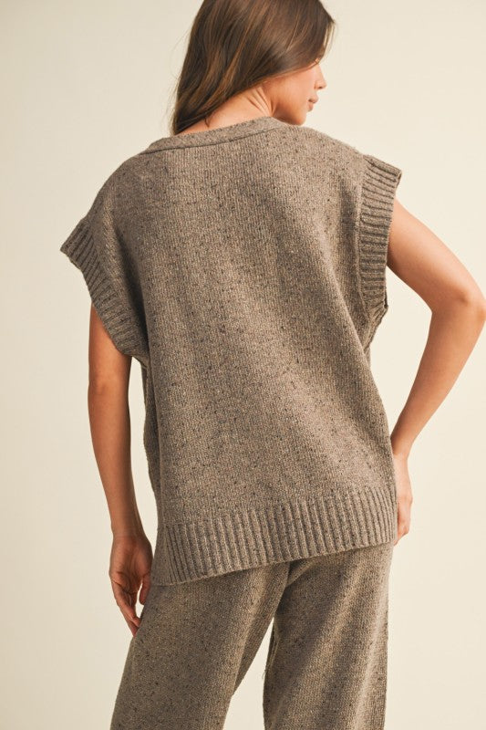 Woman wearing a brown knitted vest and pants on a beige background