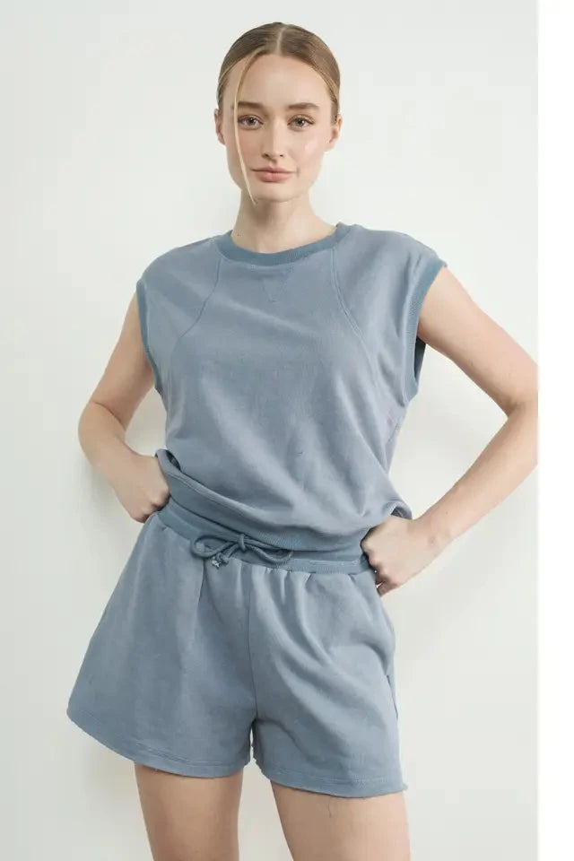 A woman wearing a sleeveless top and matching shorts in a light blue color, both made from terry fabric.