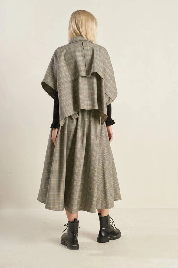 Person wearing a plaid coat and skirt set on a beige background