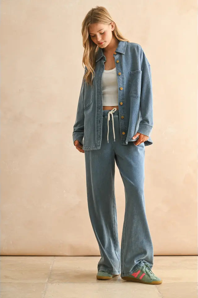 Woman wearing a denim jacket and pants with a beige background