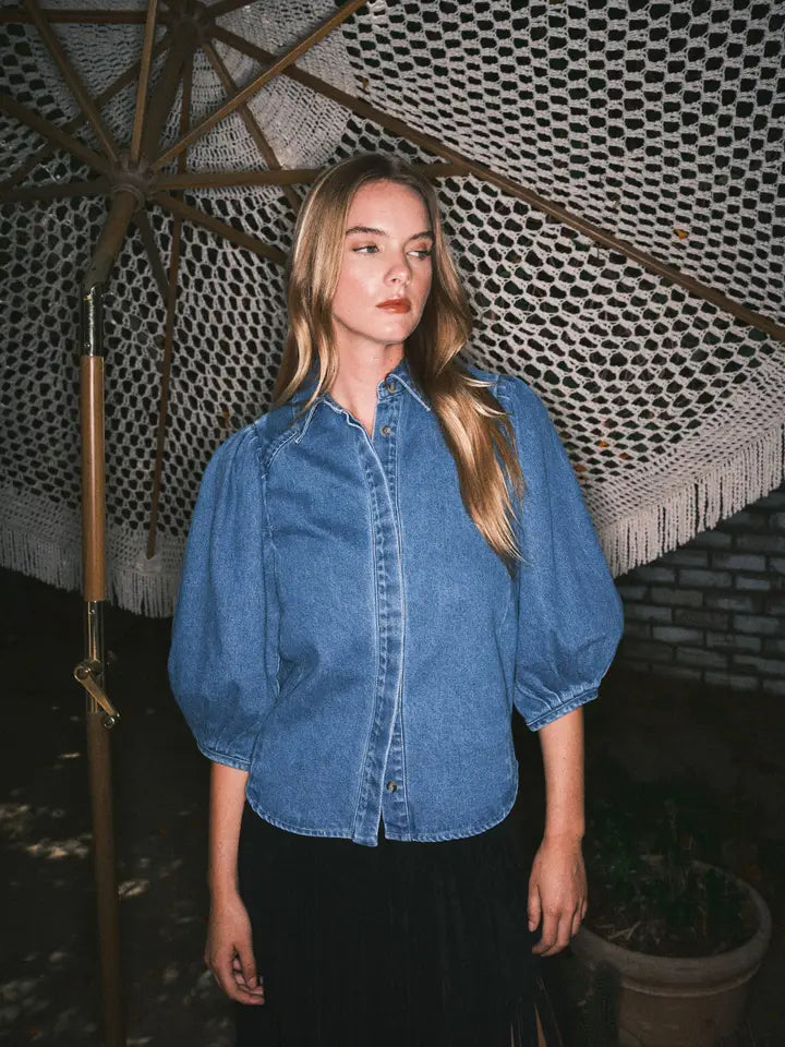 Woman wearing a blue denim shirt standing under a patterned roof