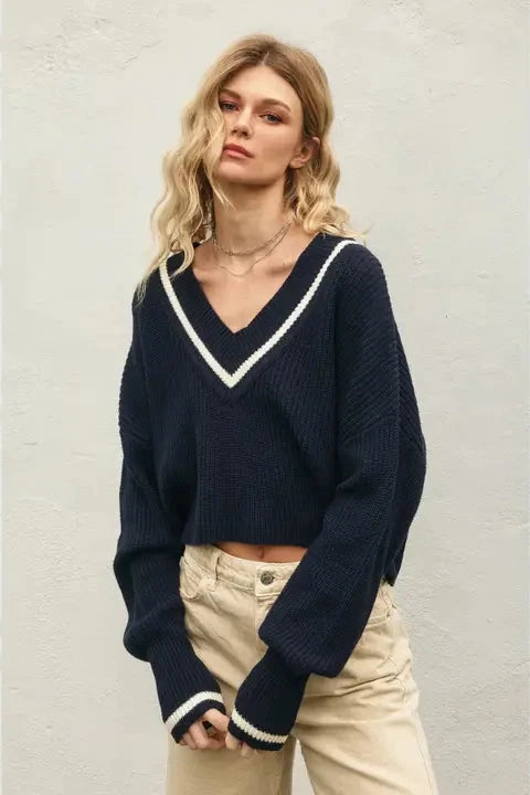 Woman wearing a navy sweater with white trim against a light background