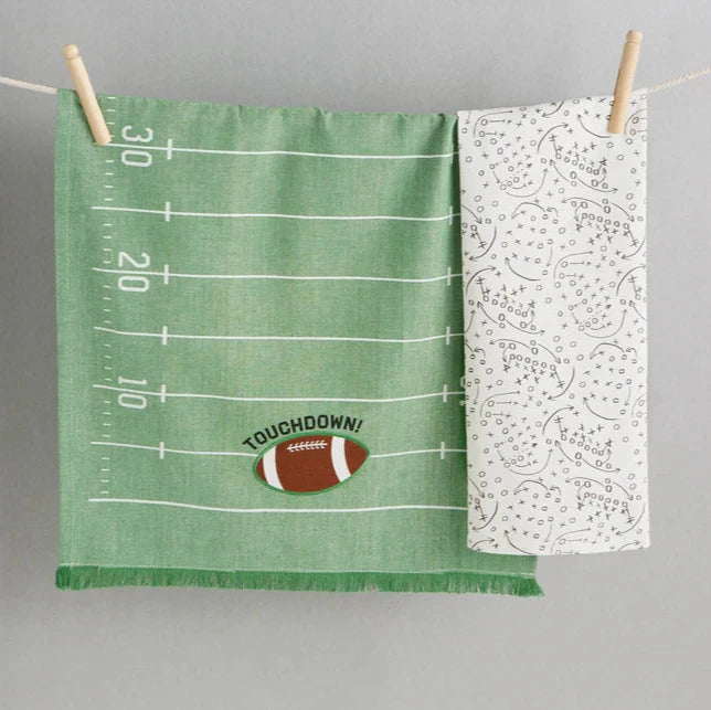 Two fabric swatches on a gray background, one green with football design and 'Touchdown!' text, the other white with black pattern.