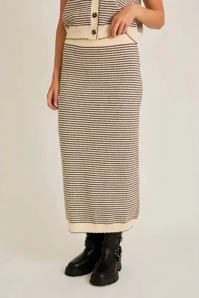 Person wearing a striped skirt and button-up top on a plain background