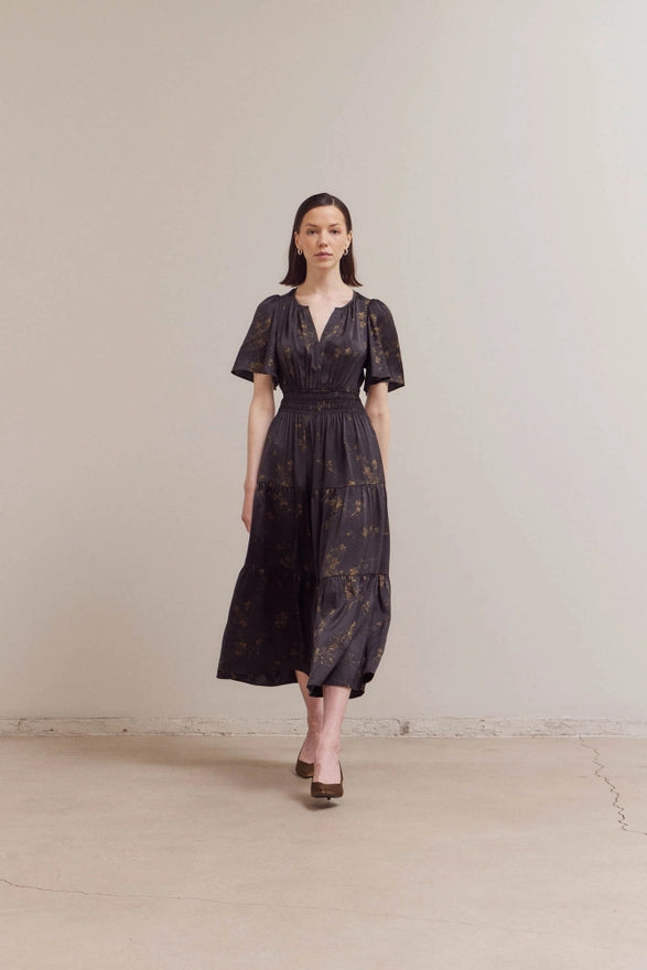 Woman wearing a dark floral dress against a plain background