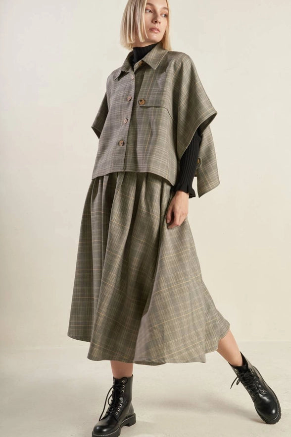 Person wearing a plaid outfit with a jacket and skirt on a plain background