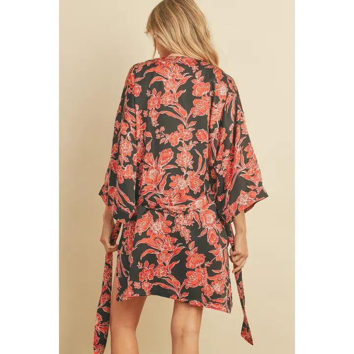 Woman wearing a floral kimono-style garment against a plain background.