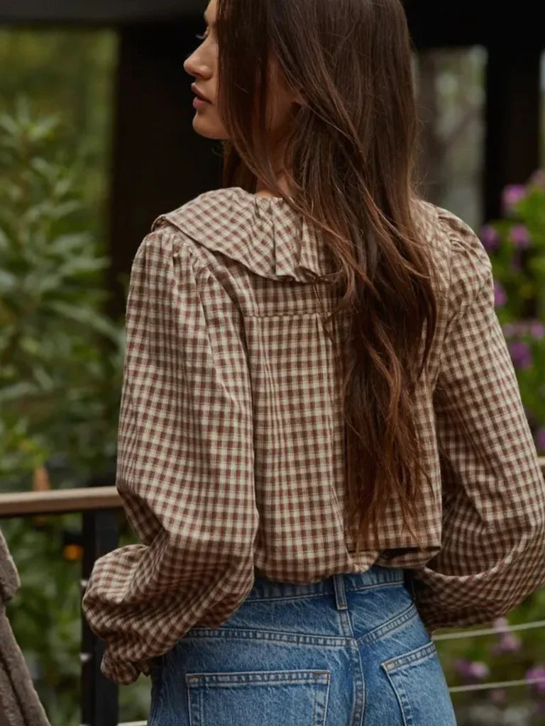 Woman wearing a plaid shirt and blue jeans with a blurred natural background