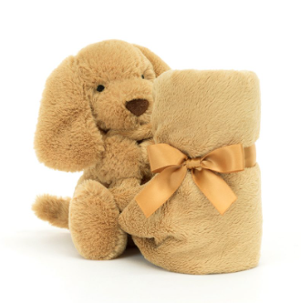 Stuffed animal dog with attached tan blanket tied in a bow.
