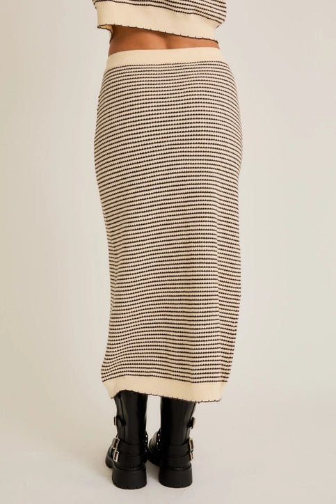 Person wearing a striped skirt with a neutral background