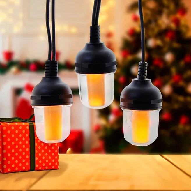 Three hanging light bulbs on a wooden surface with a blurred Christmas tree and gift in the background.