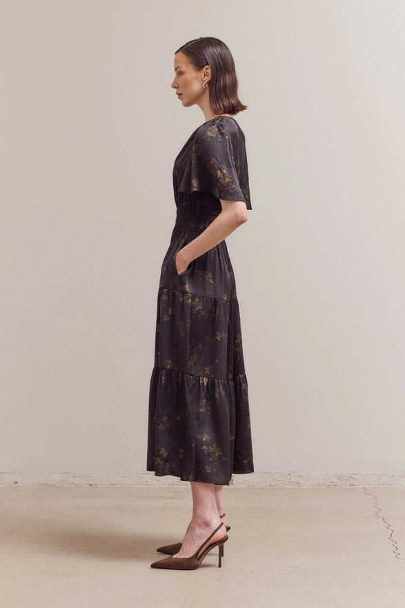 Woman wearing a black floral dress against a plain background