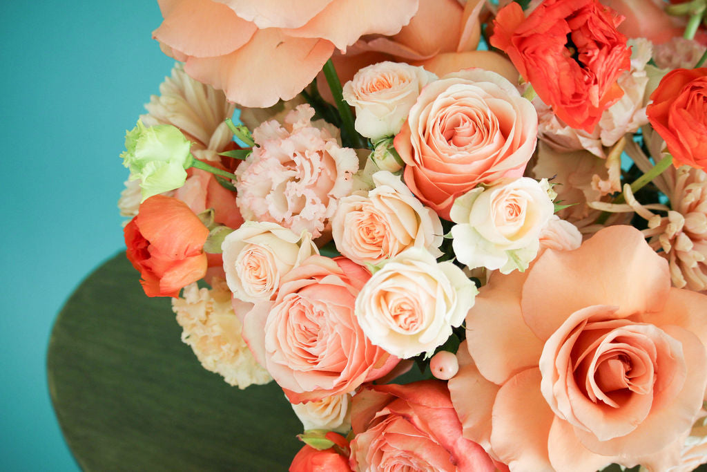 Coral floral vase arrangement in gold vase.