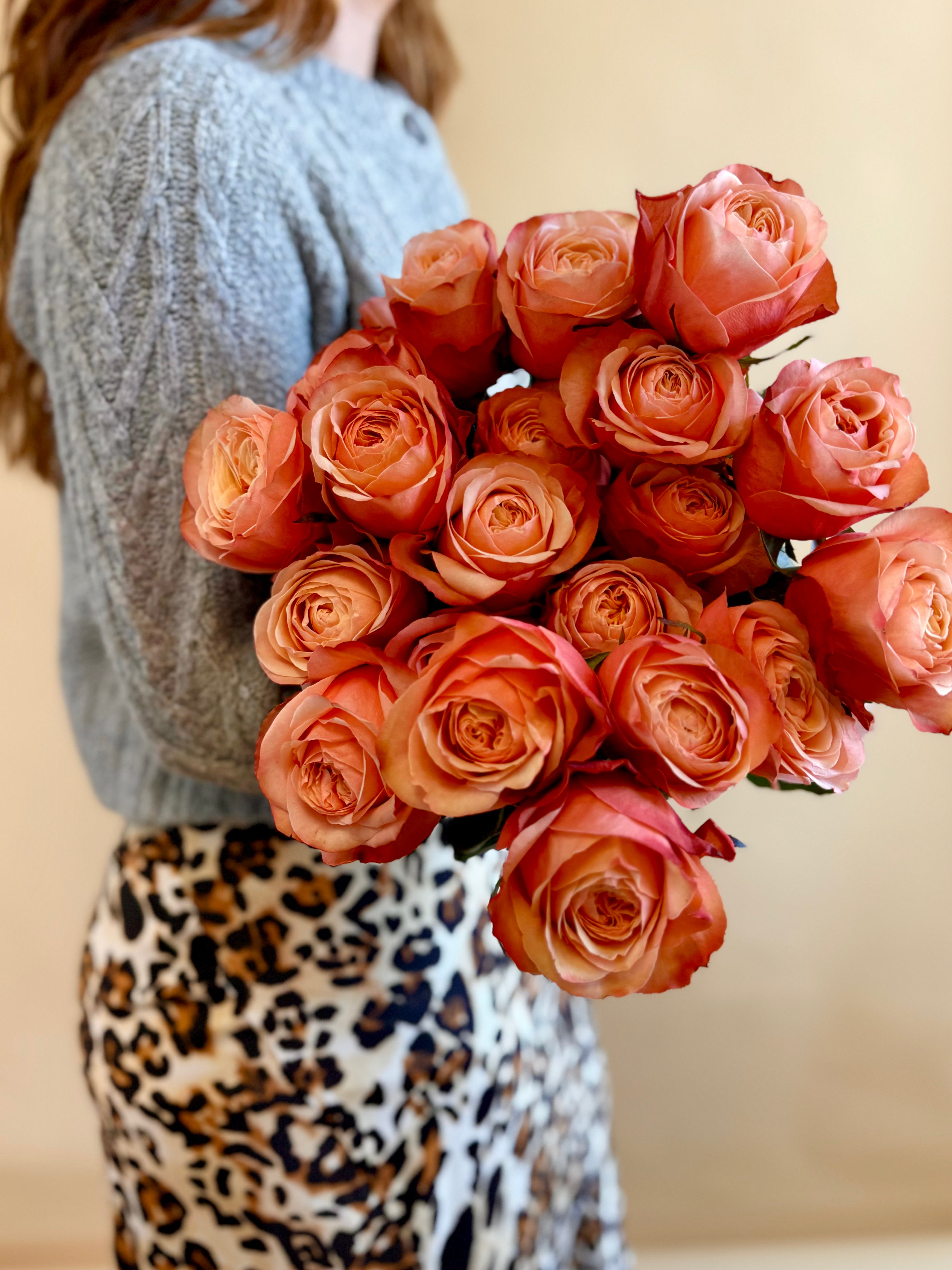 Woman holding a dozen sunset roses.