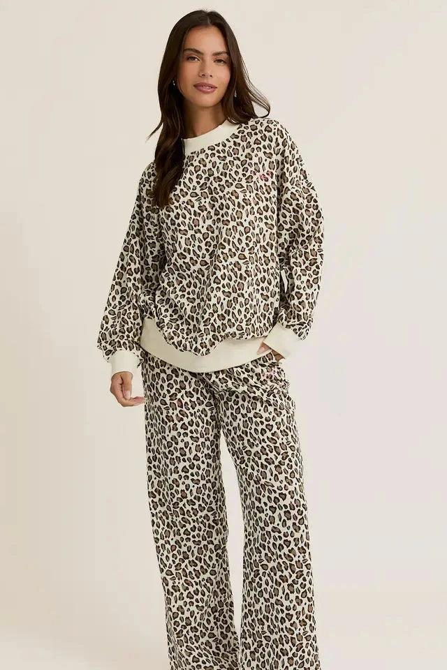 A woman wearing a leopard print crew neck sweatshirt and matching sweatpants.