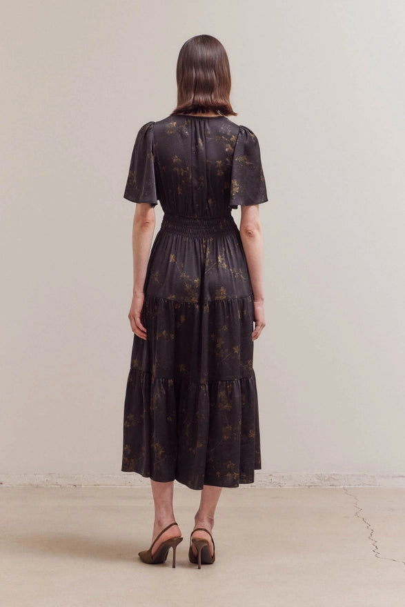 Woman wearing a black dress with a subtle pattern against a plain background