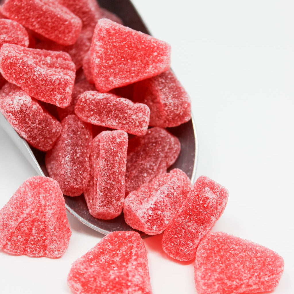 A group of pink candy gummy sweets scattered around a bowl.