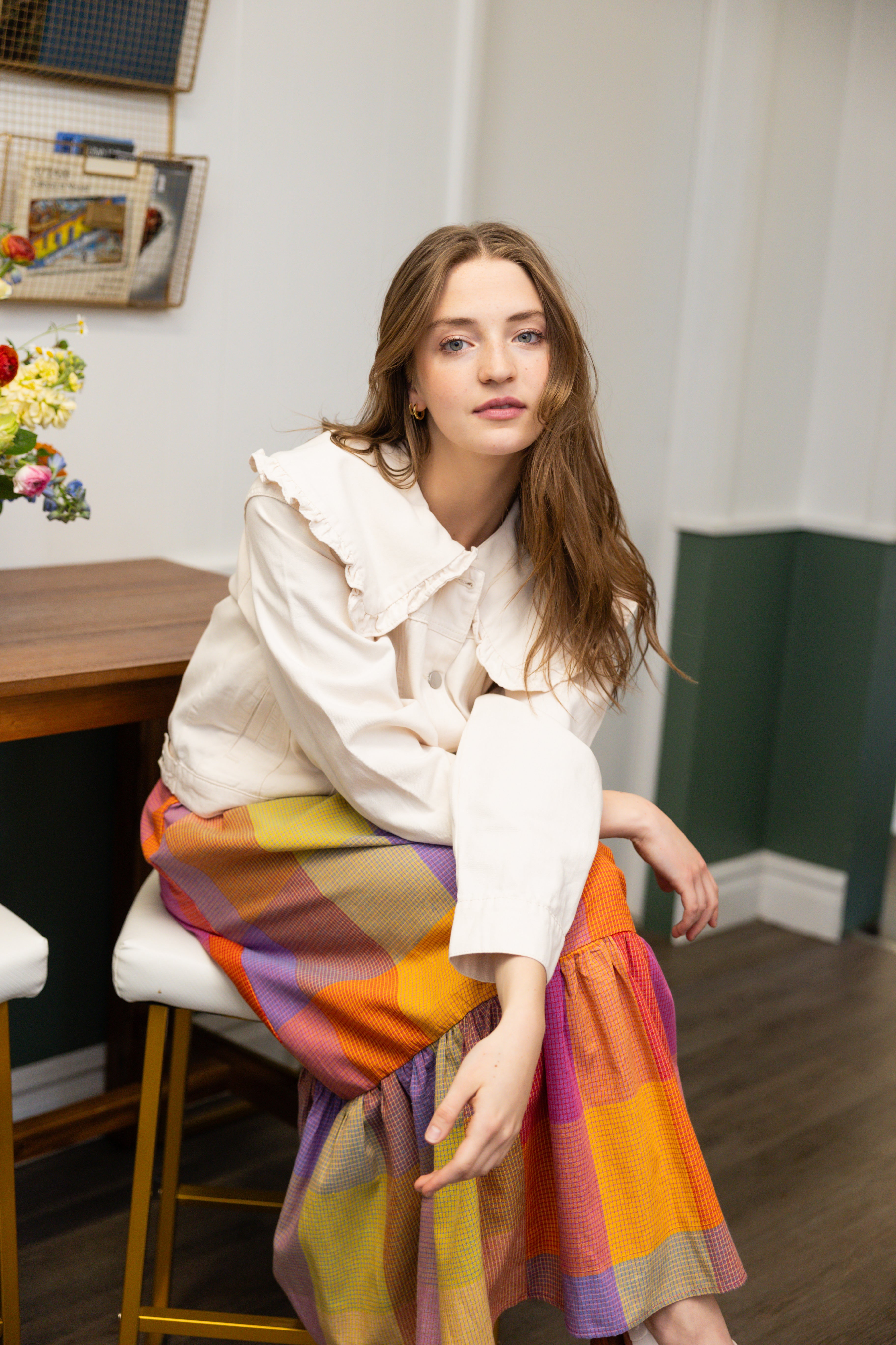 Model is wearing ruffle collar white denim jacket and colorful dress.
