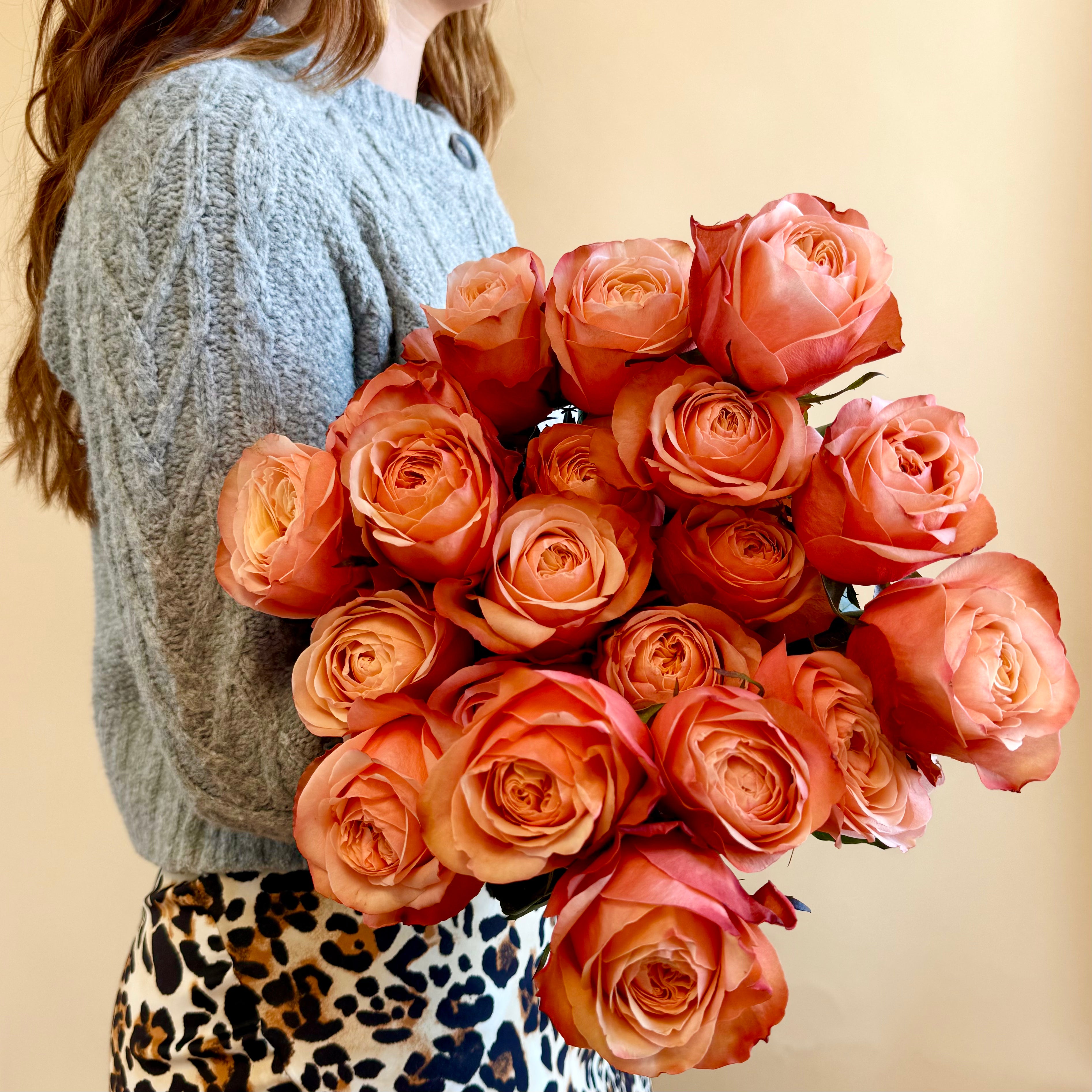 Woman holding a dozen sunset roses.