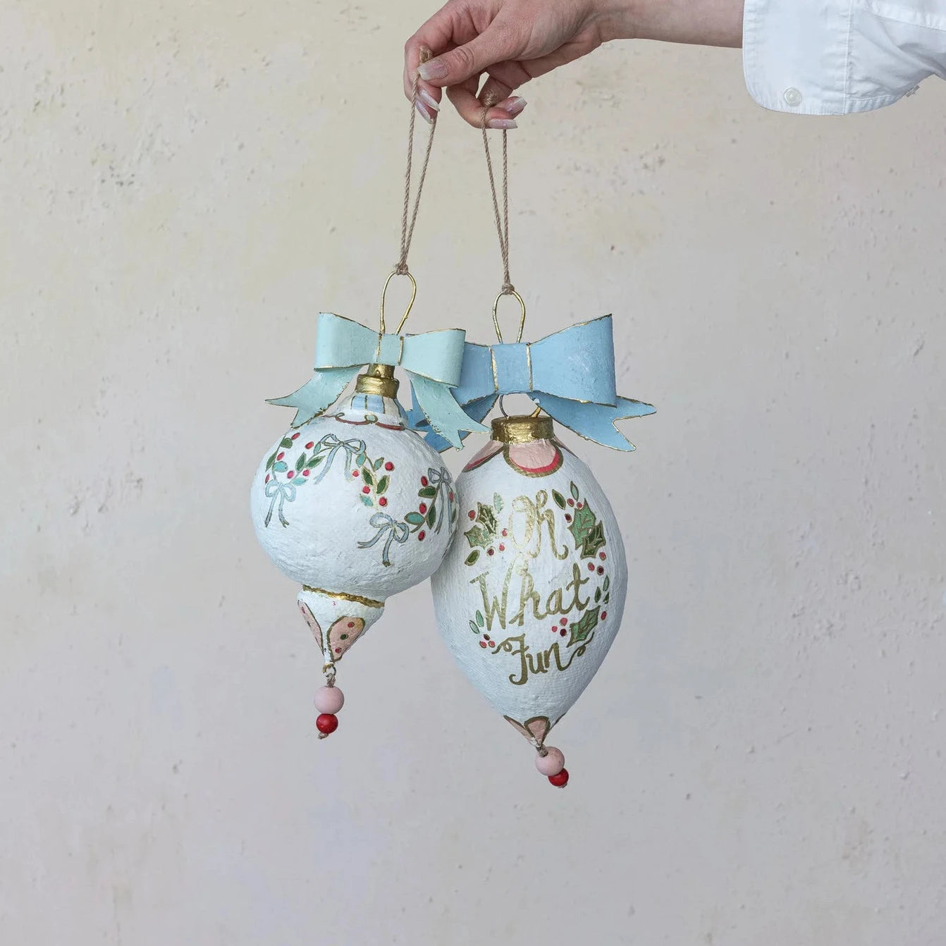 Two decorative Christmas ornaments with bows against a plain background