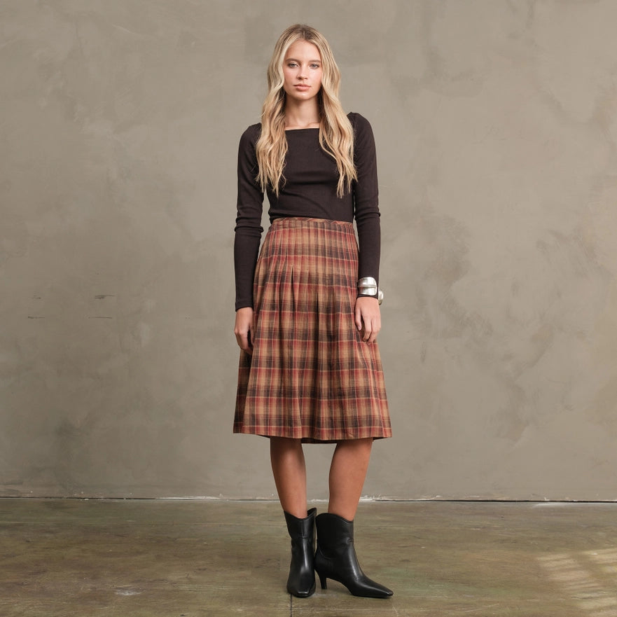 Woman wearing a plaid skirt and black top against a plain background