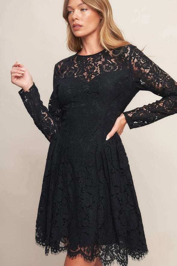 Woman wearing a black lace dress against a plain background