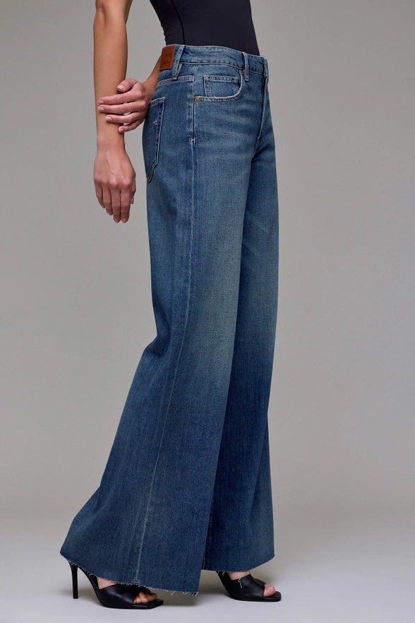 Blue wide-leg jeans worn by a person on a plain background