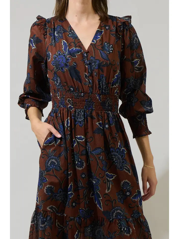 Brown dress with blue floral pattern worn by a person on a plain background