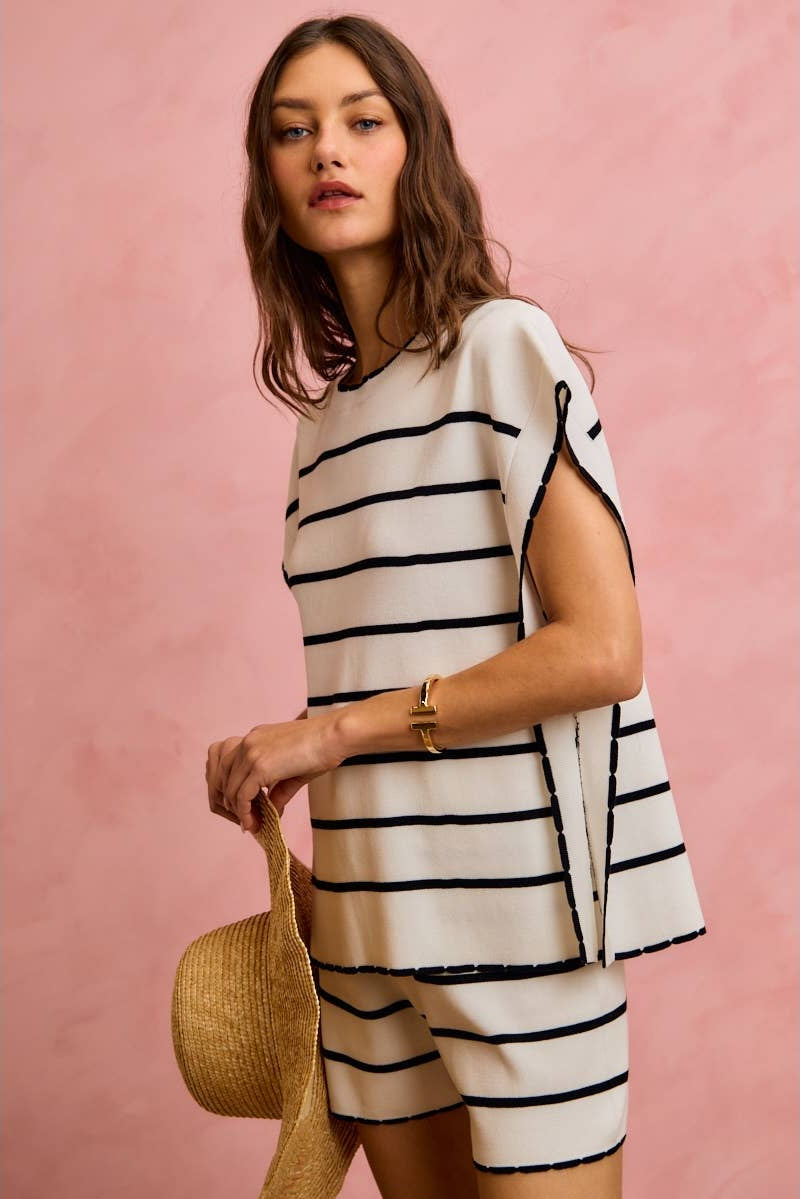 Woman wearing a black and white striped dress against a pink background