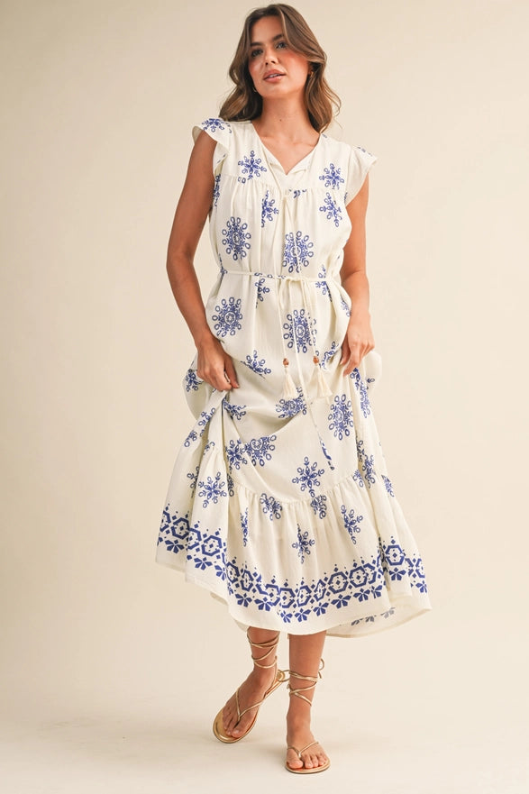 Woman wearing a white dress with blue floral patterns on a beige background