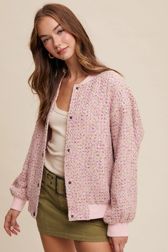 Woman wearing a pink textured jacket over a beige top and green skirt on a beige background