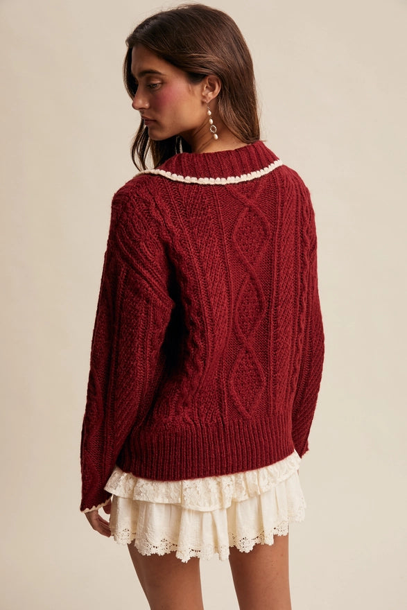 Woman wearing a red sweater with white trim against a beige background