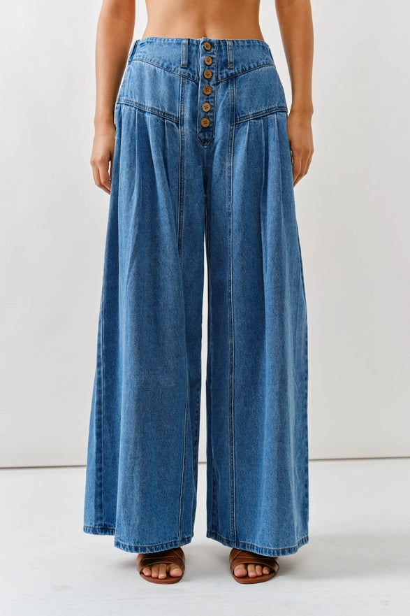 Blue denim wide-leg pants with button details on a white background