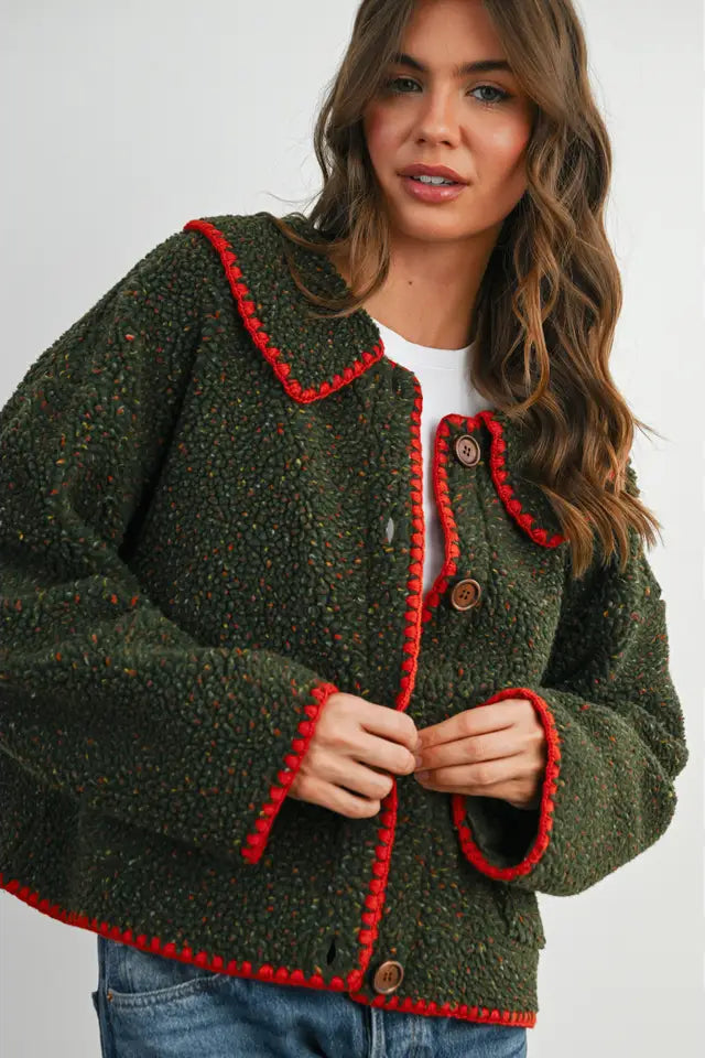 Woman wearing a green jacket with red trim on a white background