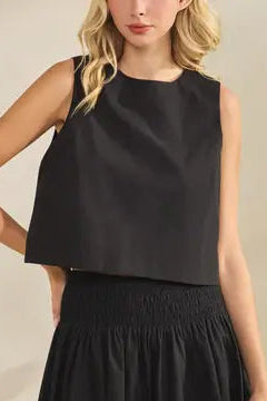 Woman wearing a black sleeveless top and skirt against a plain background