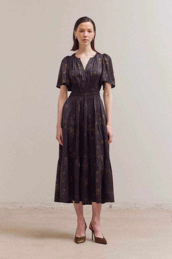 Woman wearing a black floral dress against a plain background