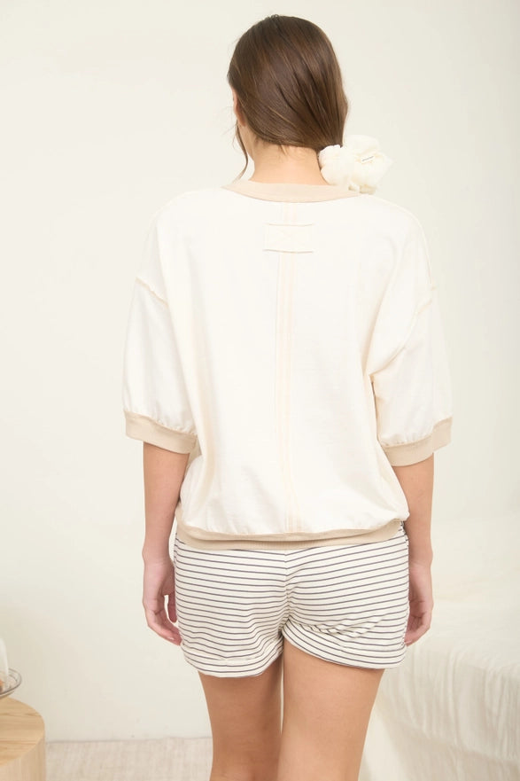 Person wearing a white top and striped shorts against a plain background