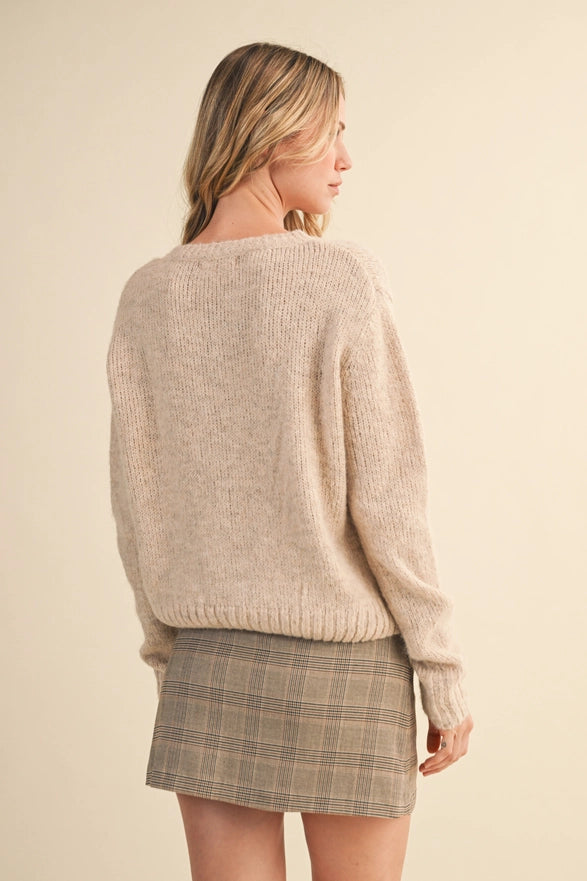 Woman wearing a beige sweater and plaid skirt on a beige background