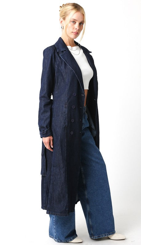 Woman wearing a long navy coat over a white top and blue jeans on a white background