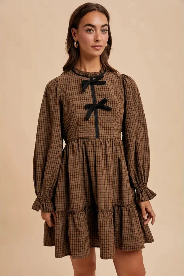 Woman wearing a brown checkered dress with black bows on a beige background