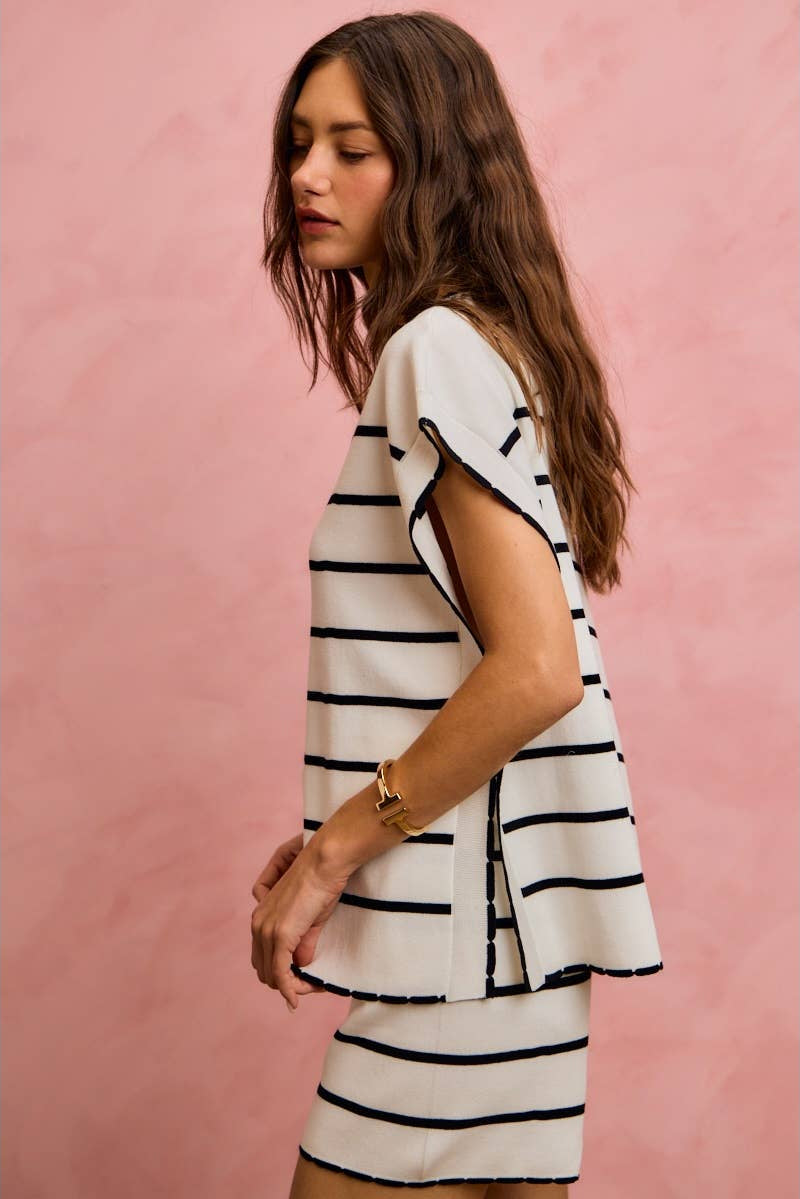 Woman wearing a white and black striped dress against a pink background