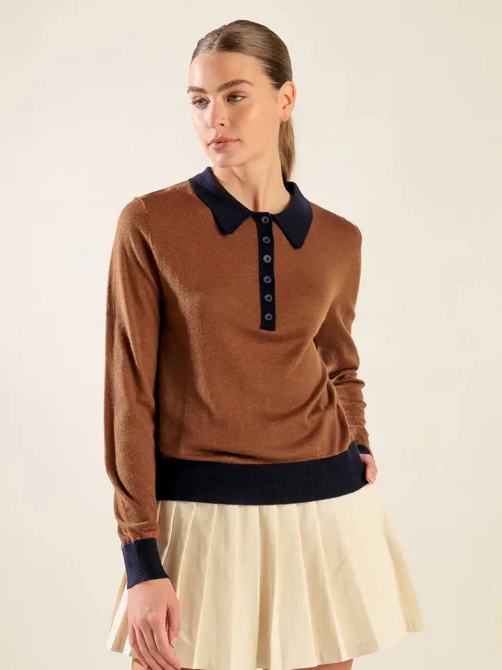 Woman wearing a brown sweater with black collar and cuffs on a beige background