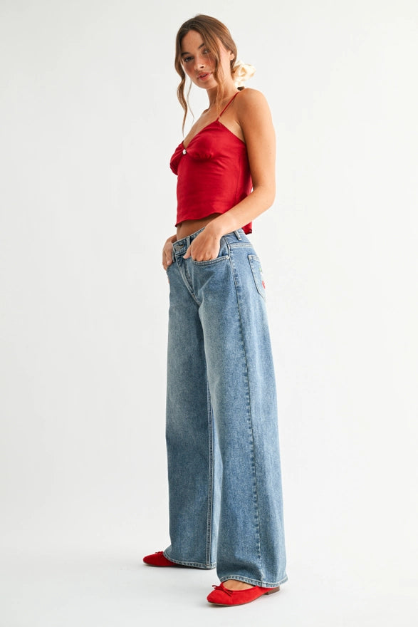 Woman wearing a red top and blue jeans on a white background