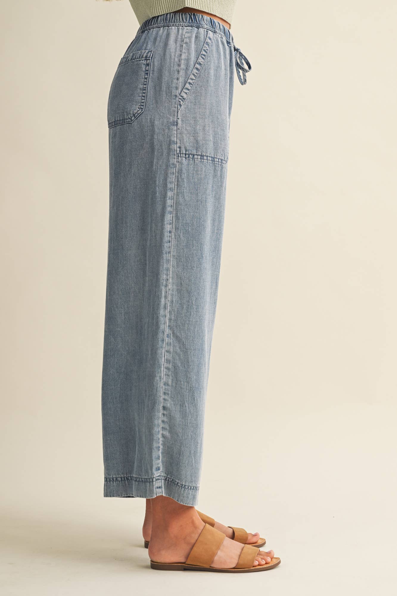 Light blue denim pants worn by a person on a beige background