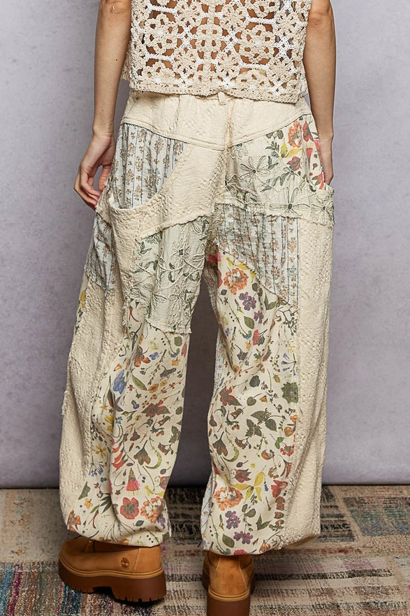 Person wearing floral and patterned pants with a plain background